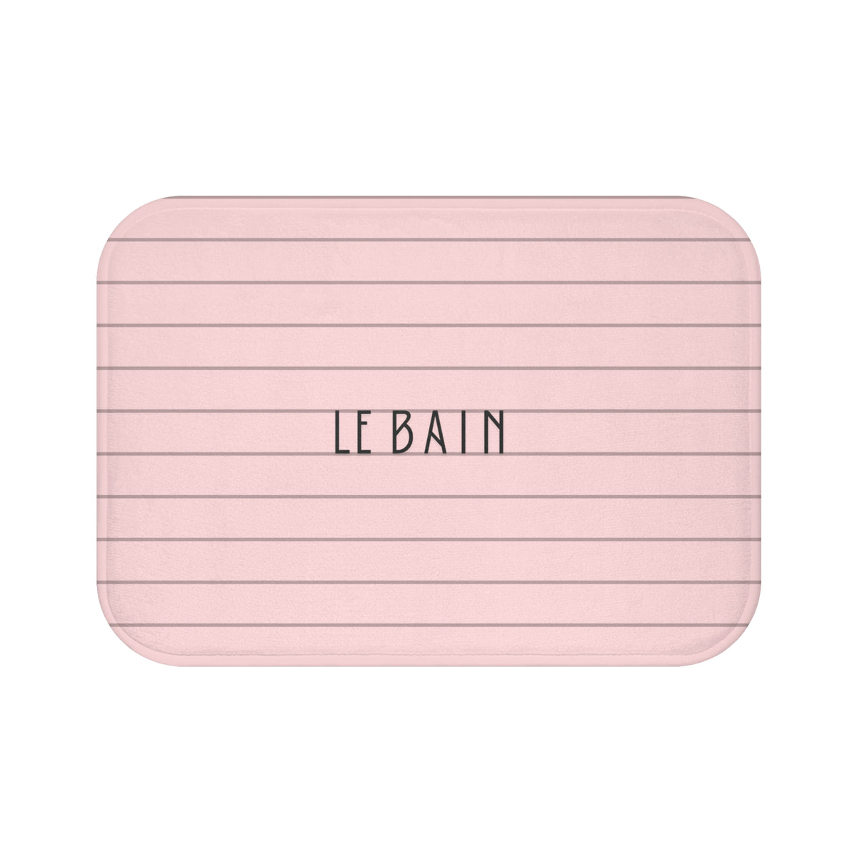 A rectangular bath mat with rounded corners, featuring a light pink background with thin horizontal dark gray lines and the word 'LE BAIN' printed in the center in a black serif font, set against a plain white background.
