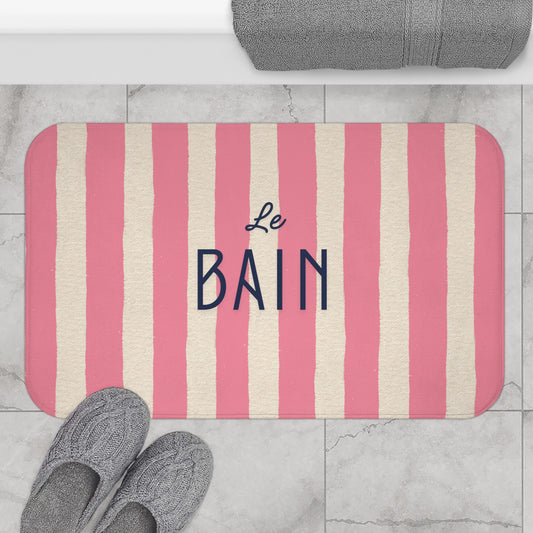 Striped bath mat with 'Le Bain' text on a bathroom floor.