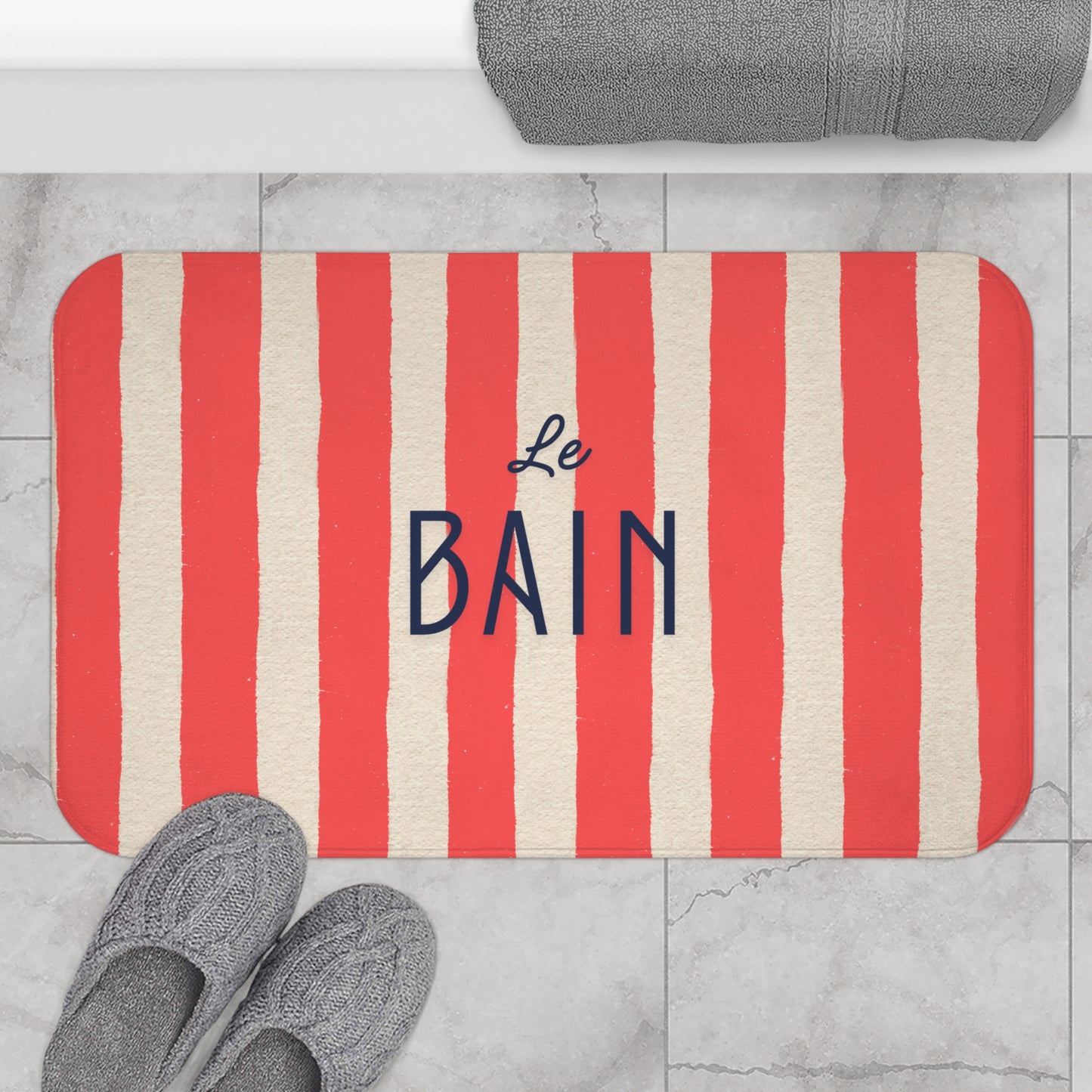 Striped bath mat with 'Le Bain' text on a bathroom floor.