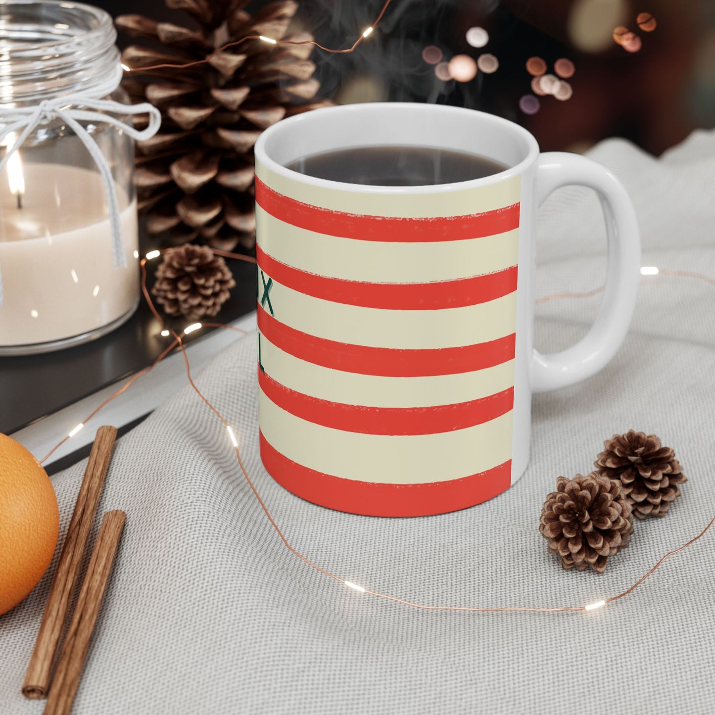 Striped mug with a festive theme on a table with candles and pinecones.