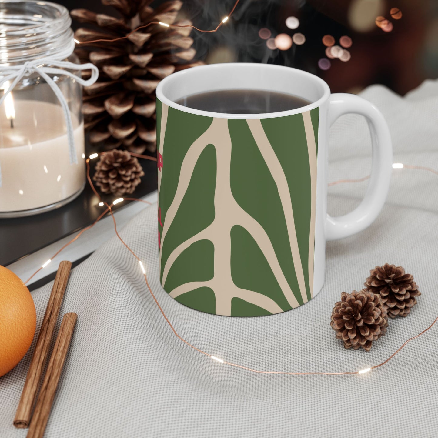 Mug with decorative pattern on a table with candles and pinecones