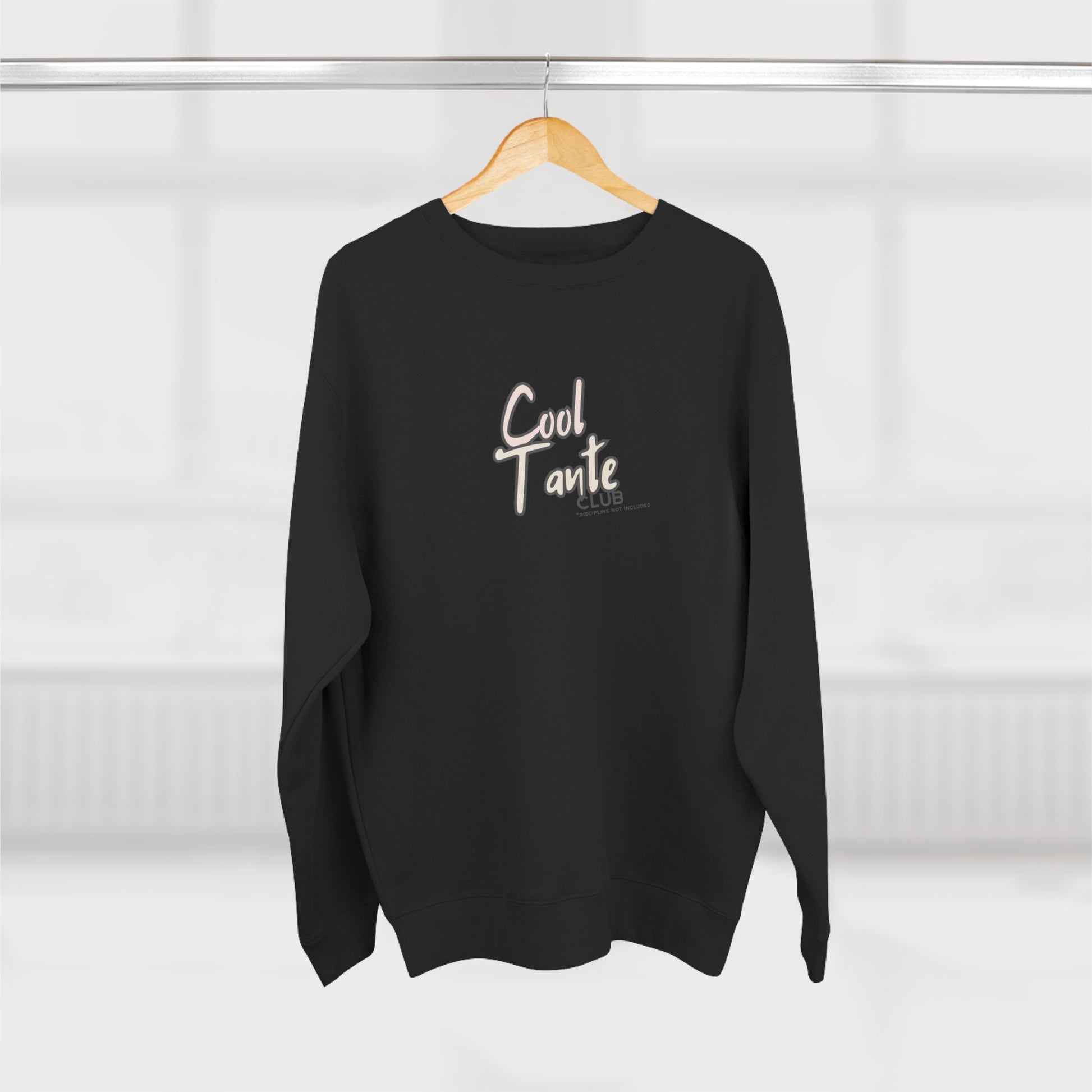 Black sweater with 'Cool Tante' text on a wooden hanger against a white background