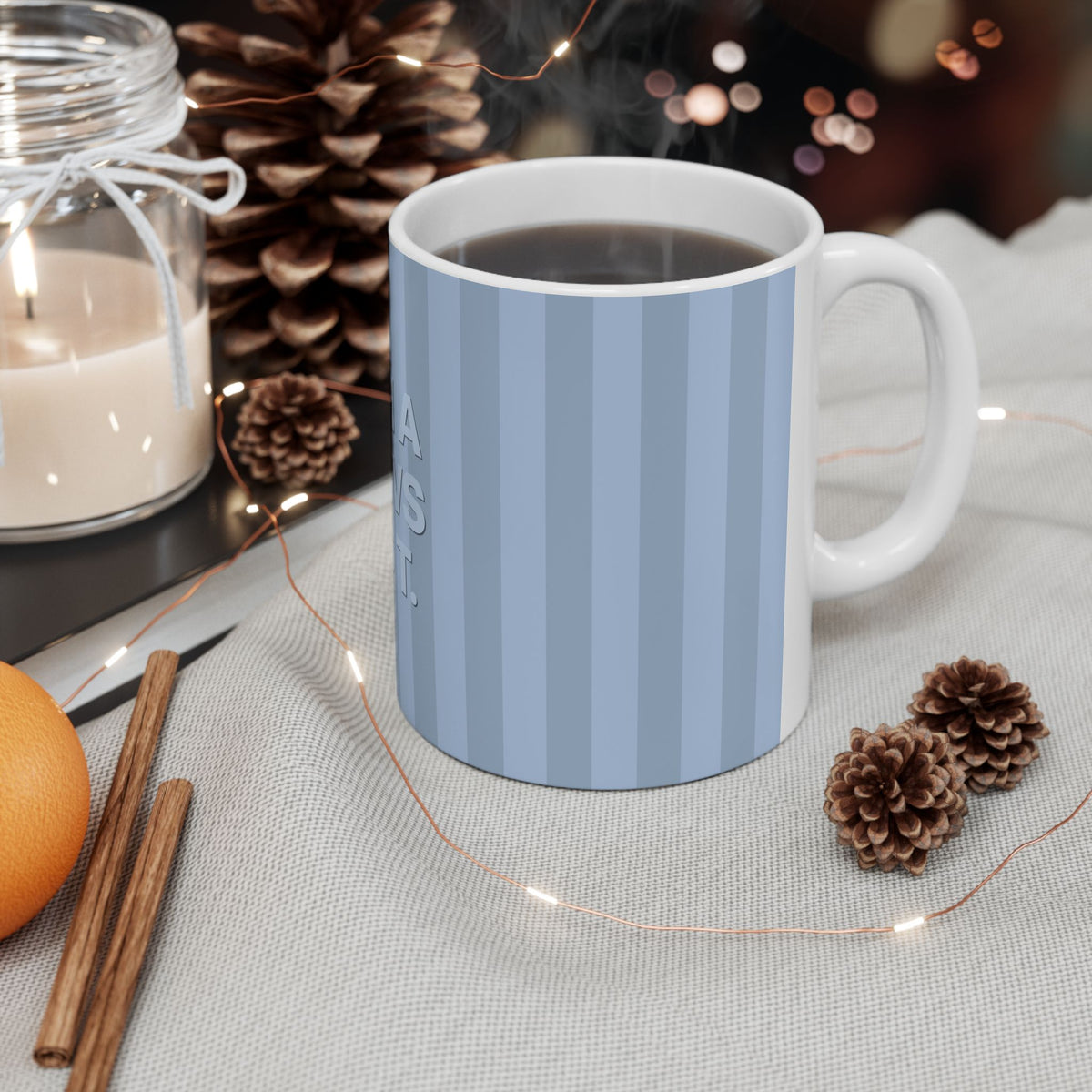 Mug with a blue design and text 'Yes, He can!' on a table with decorative items.
