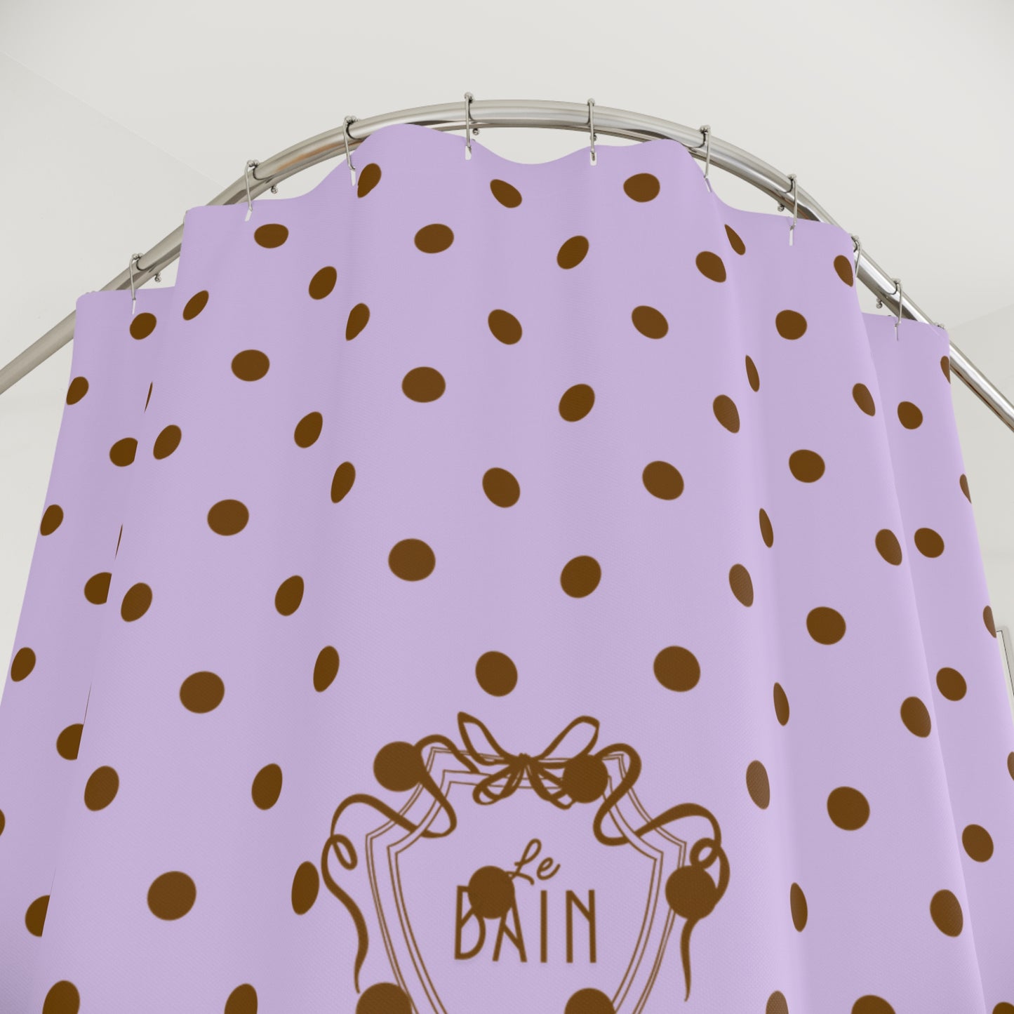 Lilac shower curtain with brown polka dots and 'Le Bain' logo on a white background