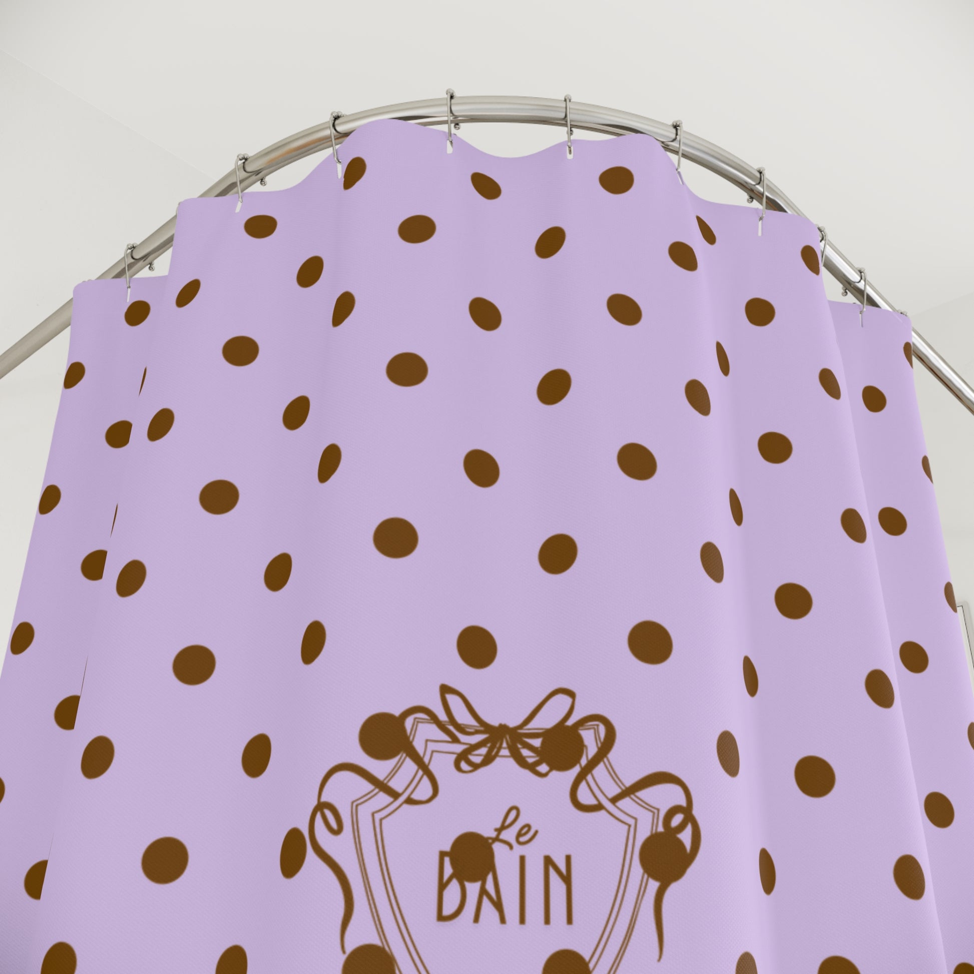 Lilac shower curtain with brown polka dots and 'Le Bain' logo on a white background