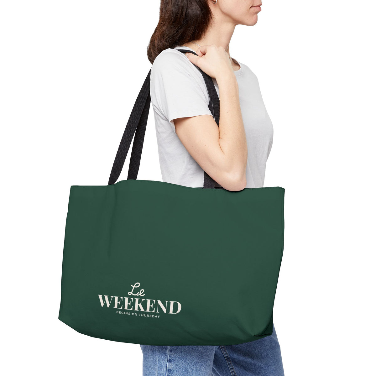 Person holding a green tote bag with 'Le Weekend' text on a white background