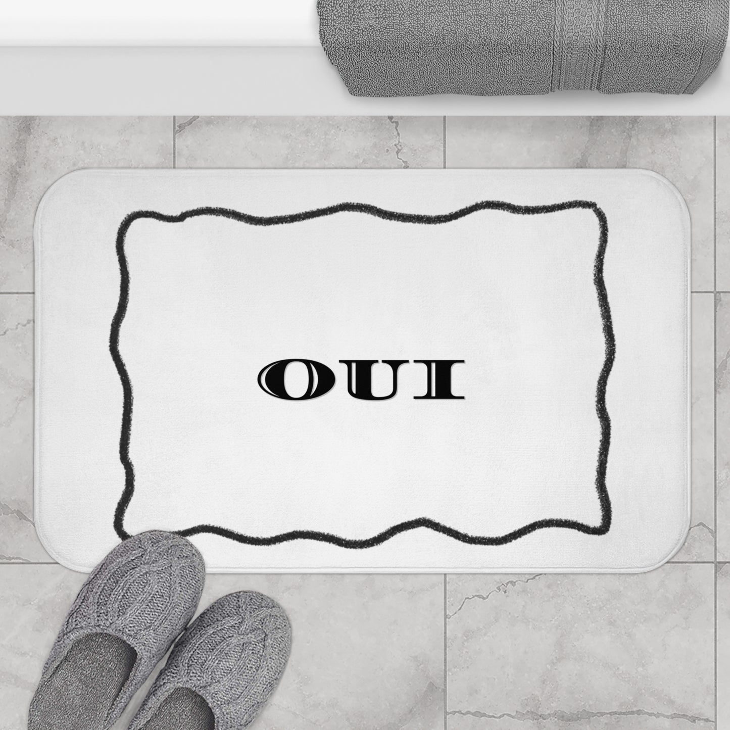 Bath mat with 'OUI' text on a bathroom floor