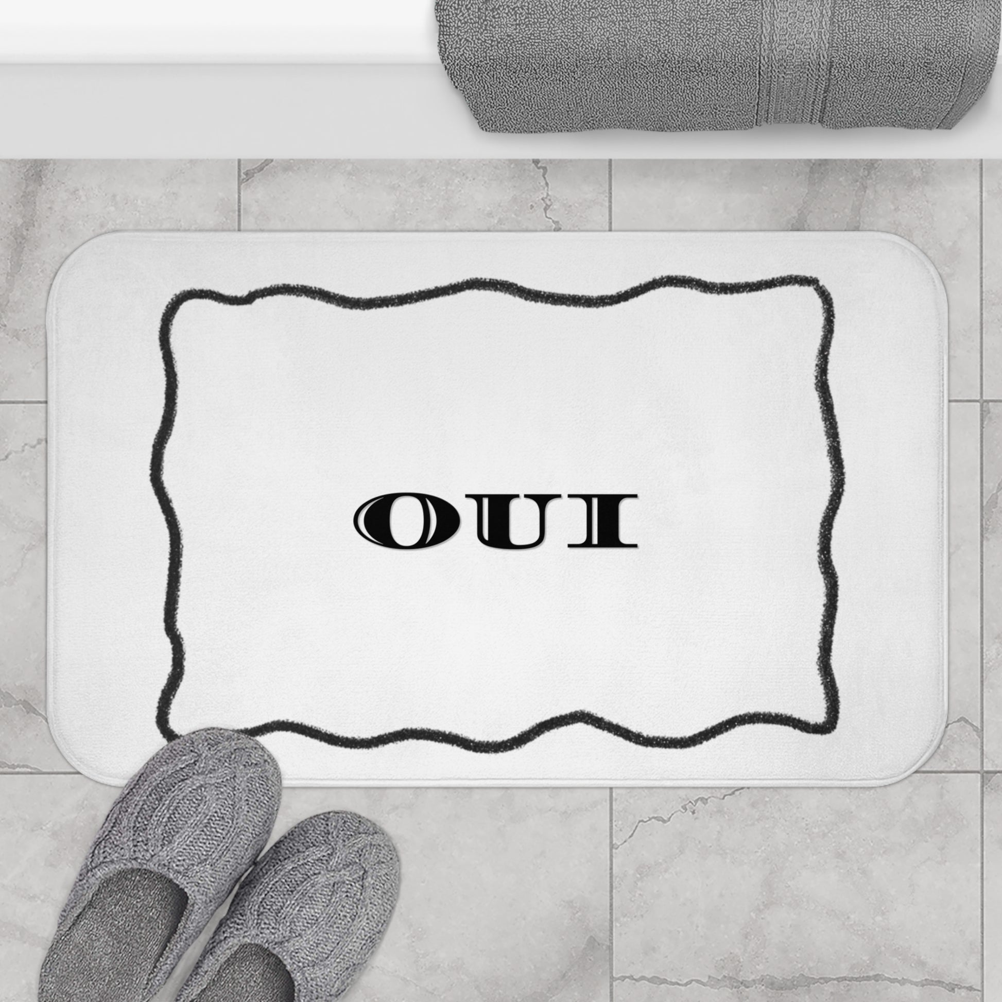 Bath mat with 'OUI' text on a bathroom floor