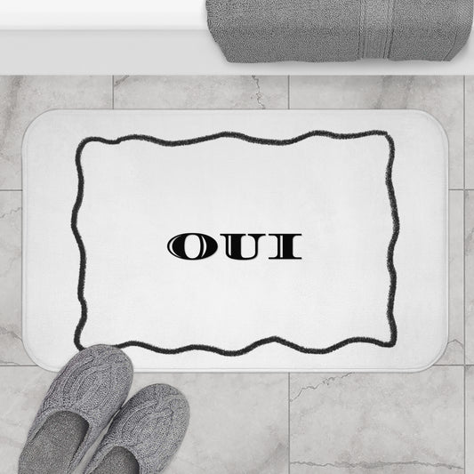 Bath mat with 'OUI' text on a bathroom floor