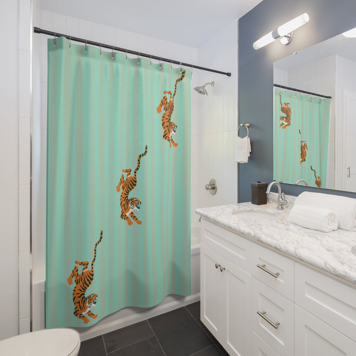 A mint green shower curtain with orange and black tiger illustrations hanging in a modern white and blue-gray bathroom.