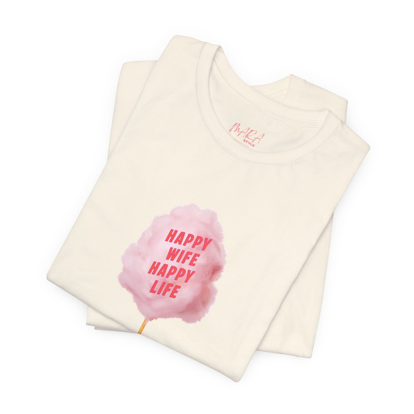 A folded cream-colored t-shirt with a pink watercolor cotton candy graphic on the front that reads 'HAPPY WIFE HAPPY LIFE' in pink text. The inside collar shows the brand name 'M+K!'.