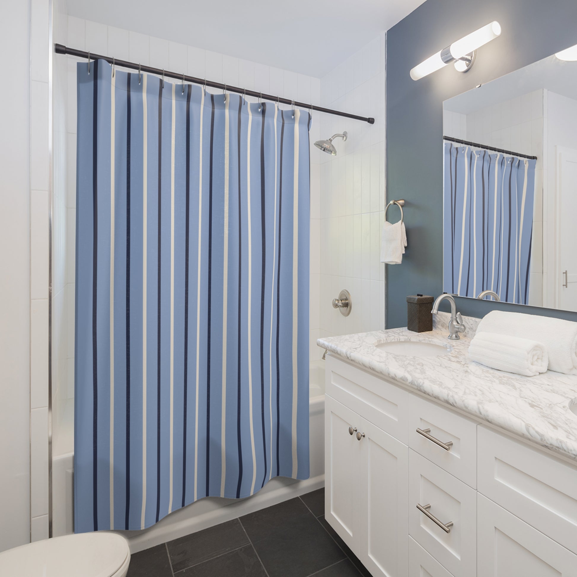 Bathroom with a blue striped shower curtain, white vanity, and mirror.