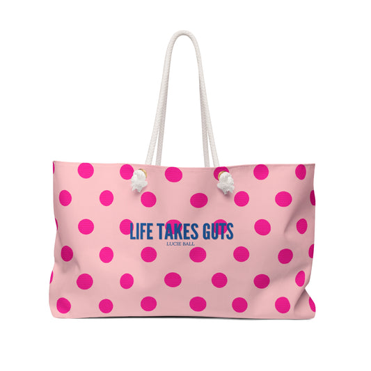 Pink polka dot bag with 'Life Takes Guts' text on a white background
