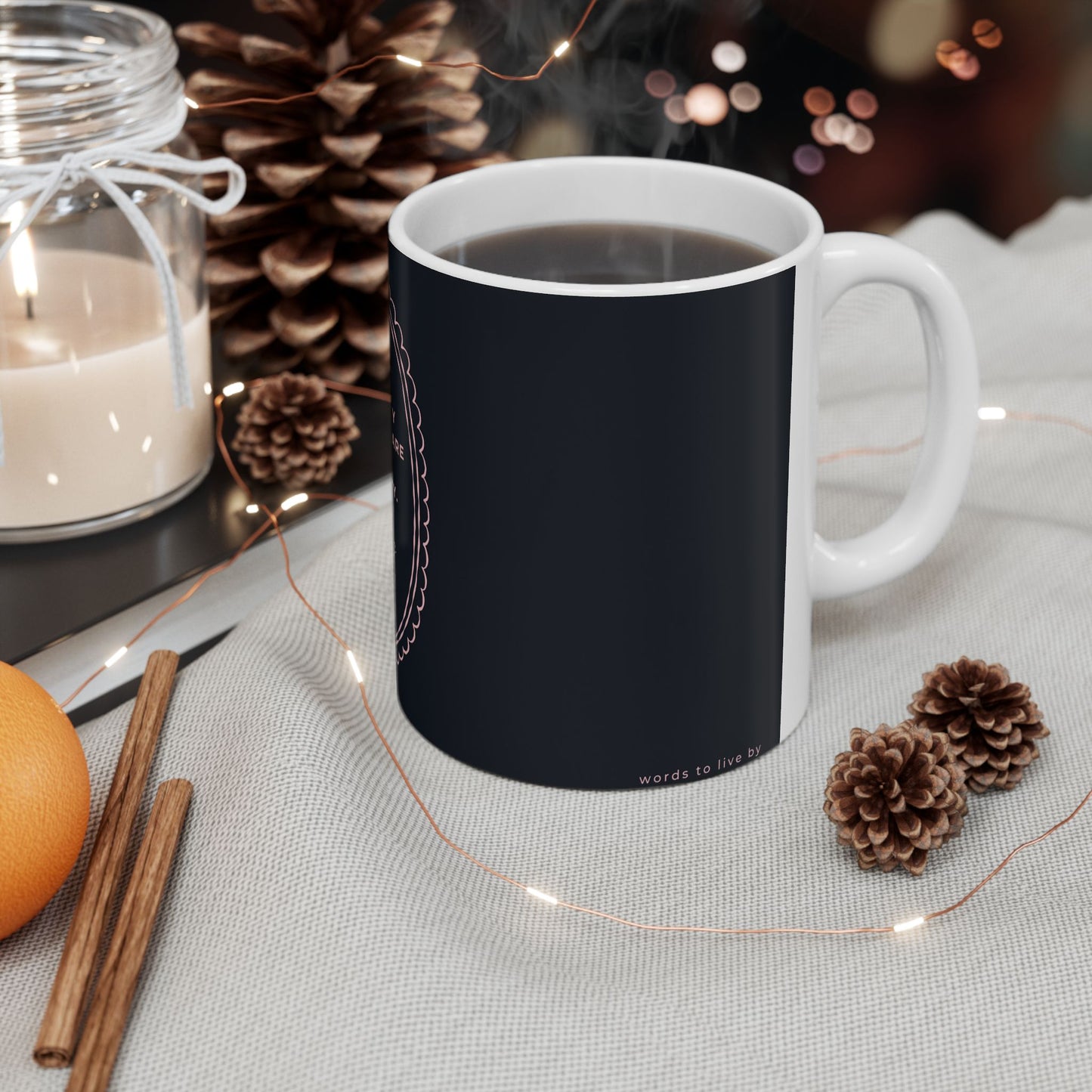 Black mug with text and graphics on a table with decorative items