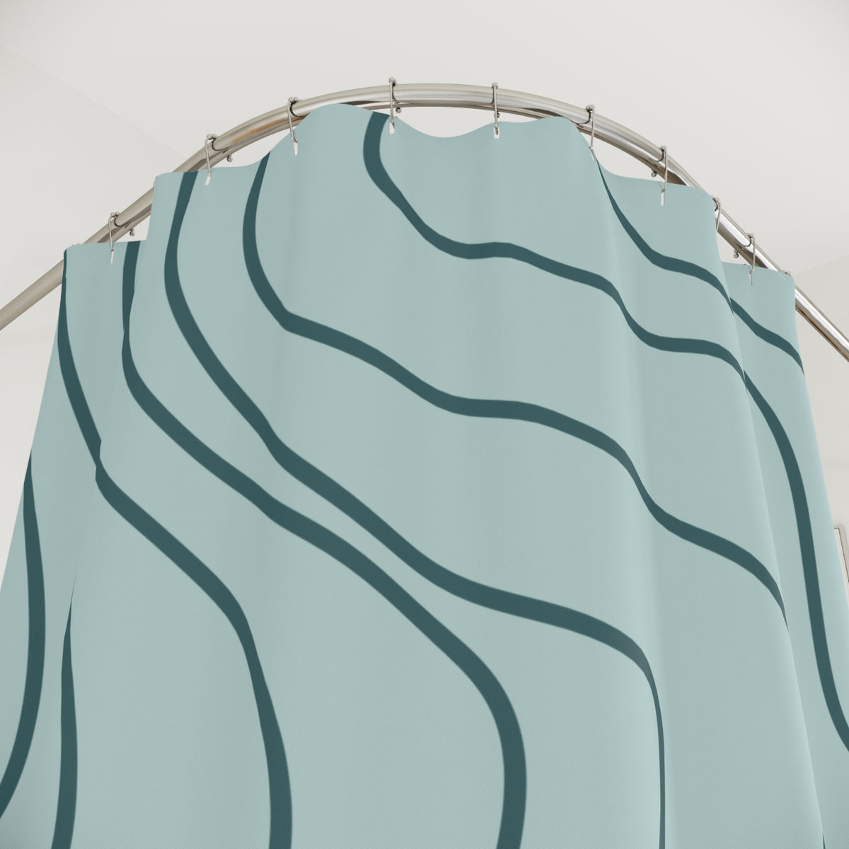 A light blue shower curtain with a dark teal wavy line pattern, hanging from a curved metal rod against a plain white wall.
