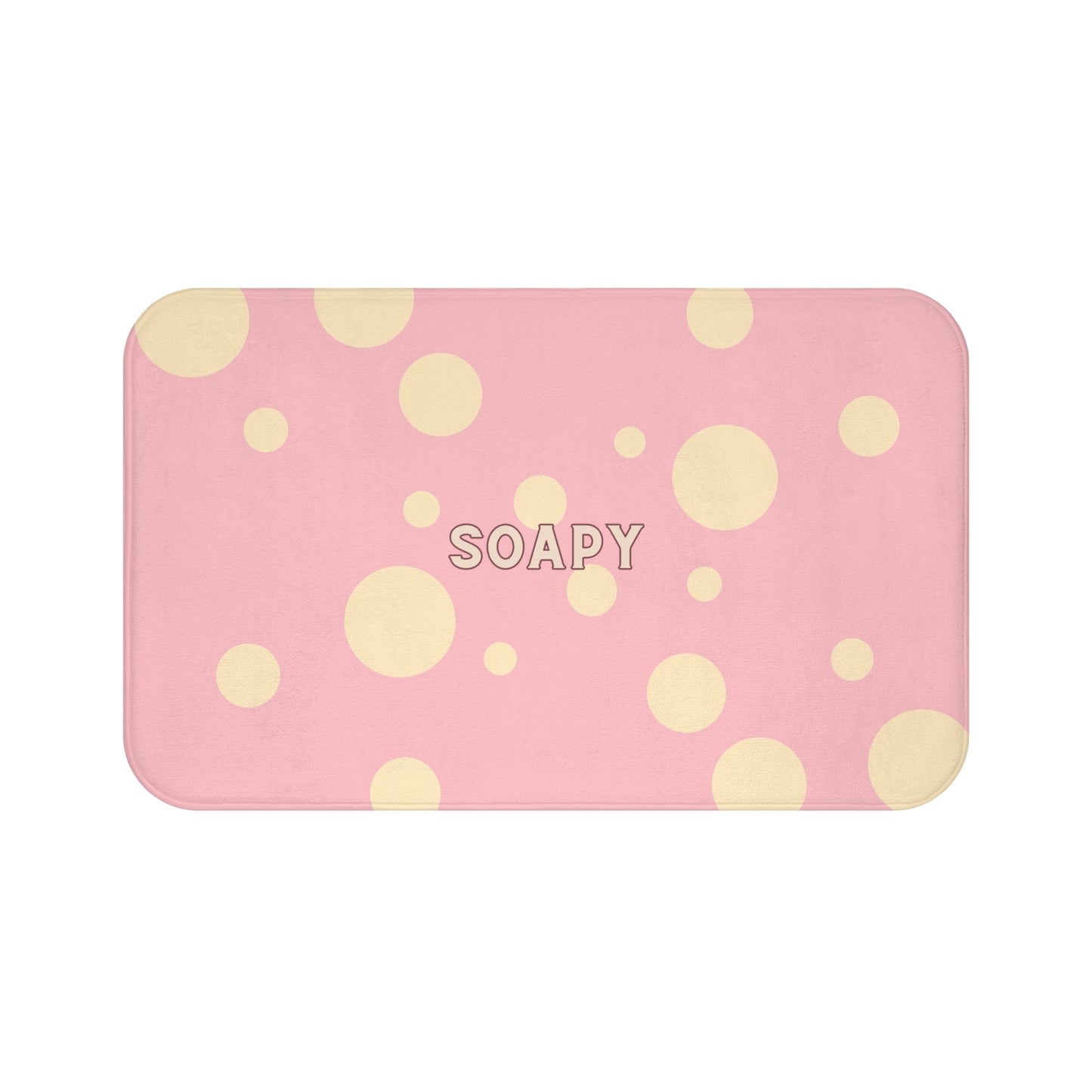 A rectangular pink bath mat with rounded corners, decorated with a pattern of light yellow polka dots and the word 'SOAPY' printed in the center, shown on a plain white background.