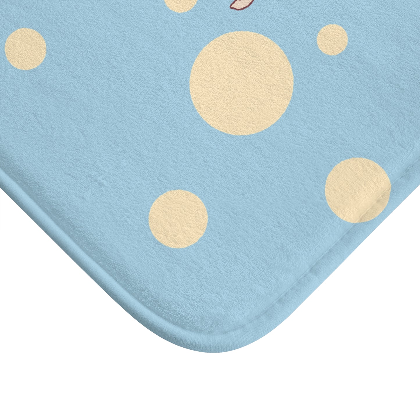 A close-up of a light blue fabric item with a soft texture and scattered beige polka dots, showing the rounded corner against a white background.