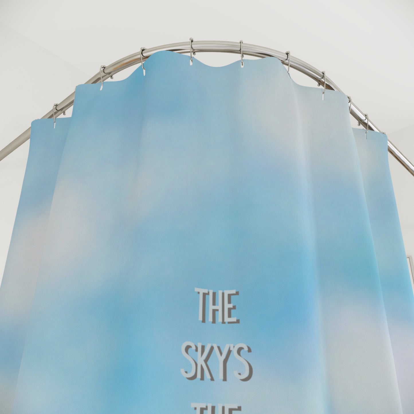 Blue gradient shower curtain with 'The Sky's The Limit' text on a metal rod.