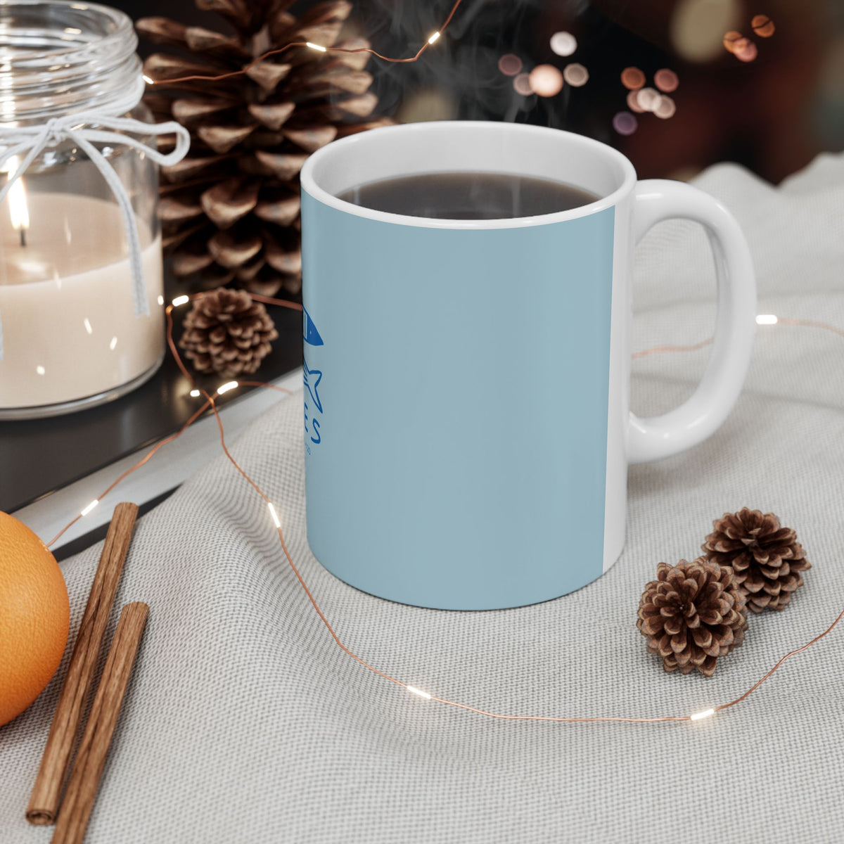Striped mug with a warm beverage on a cozy setting with candles and pinecones.