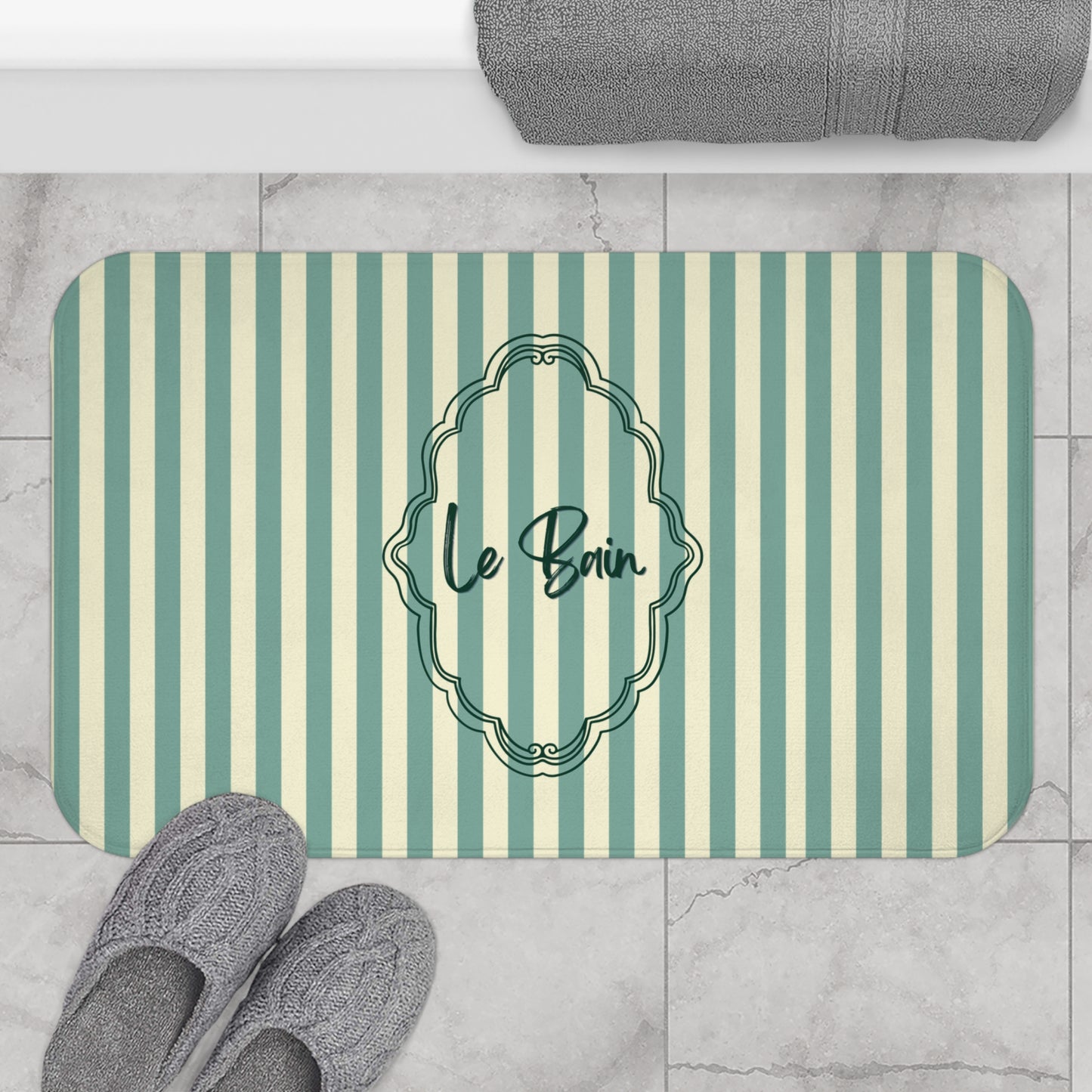 Striped bath mat with 'Le Bain' text on a bathroom floor.