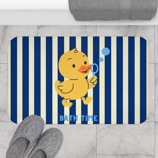A rectangular bath mat with rounded corners, featuring a yellow cartoon duck blowing blue bubbles on a navy and cream vertical stripe background. The words 'BATH TIME' are printed in blue near the bottom.