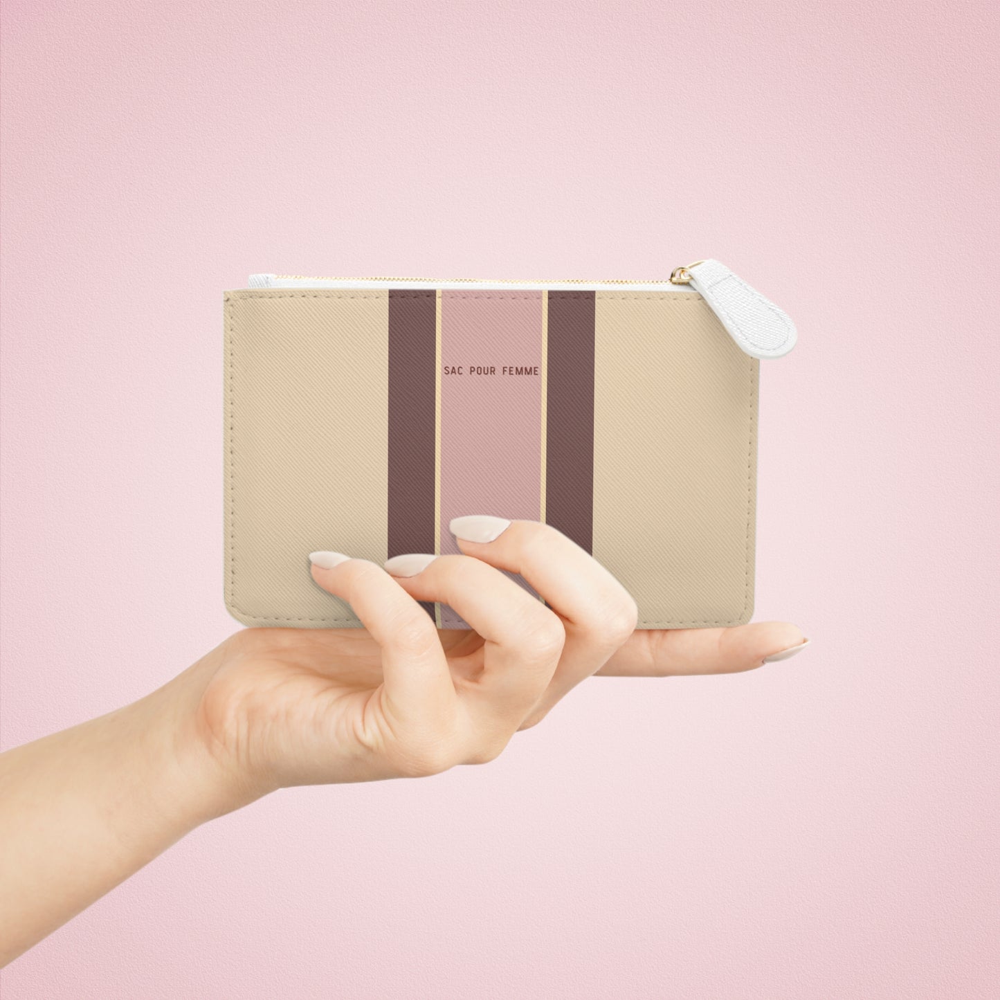 Hand holding a striped pouch with a pink background