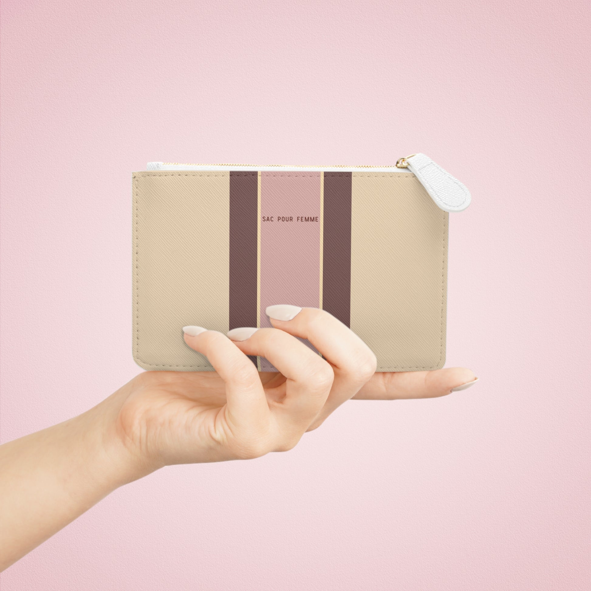 Hand holding a striped pouch with a pink background