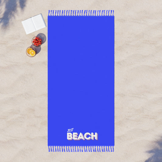 Blue beach towel with 'Just Beach' text on a sandy background