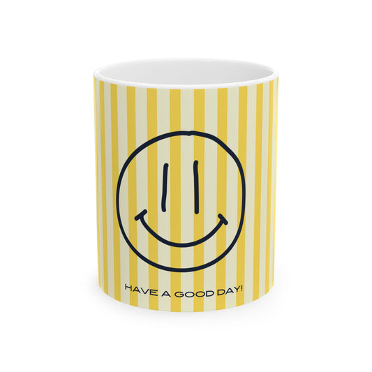 A white ceramic mug with yellow and cream vertical stripes, featuring a black smiley face graphic and the text 'HAVE A GOOD DAY!' printed near the bottom.
