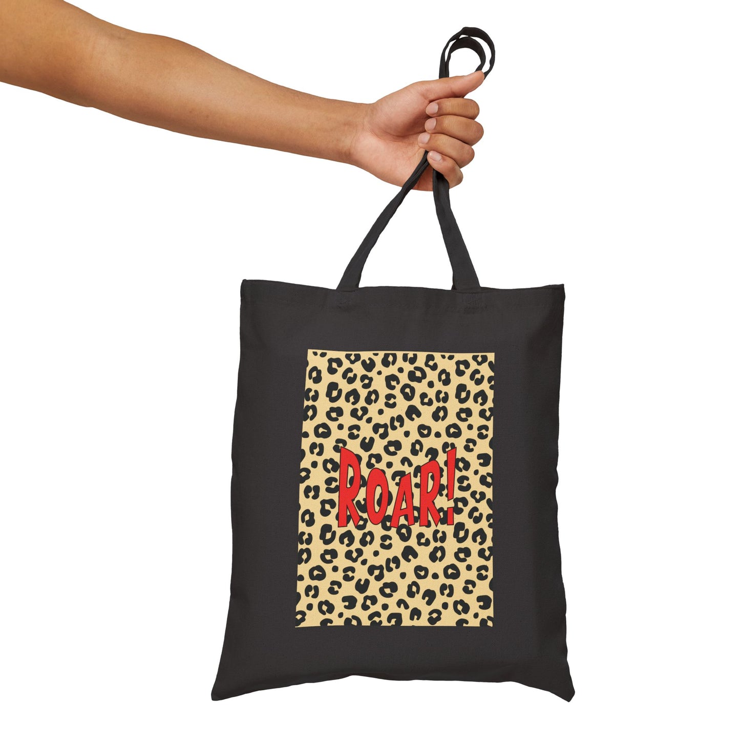 Black tote bag with leopard print and 'ROAR!' text held by a hand on a white background