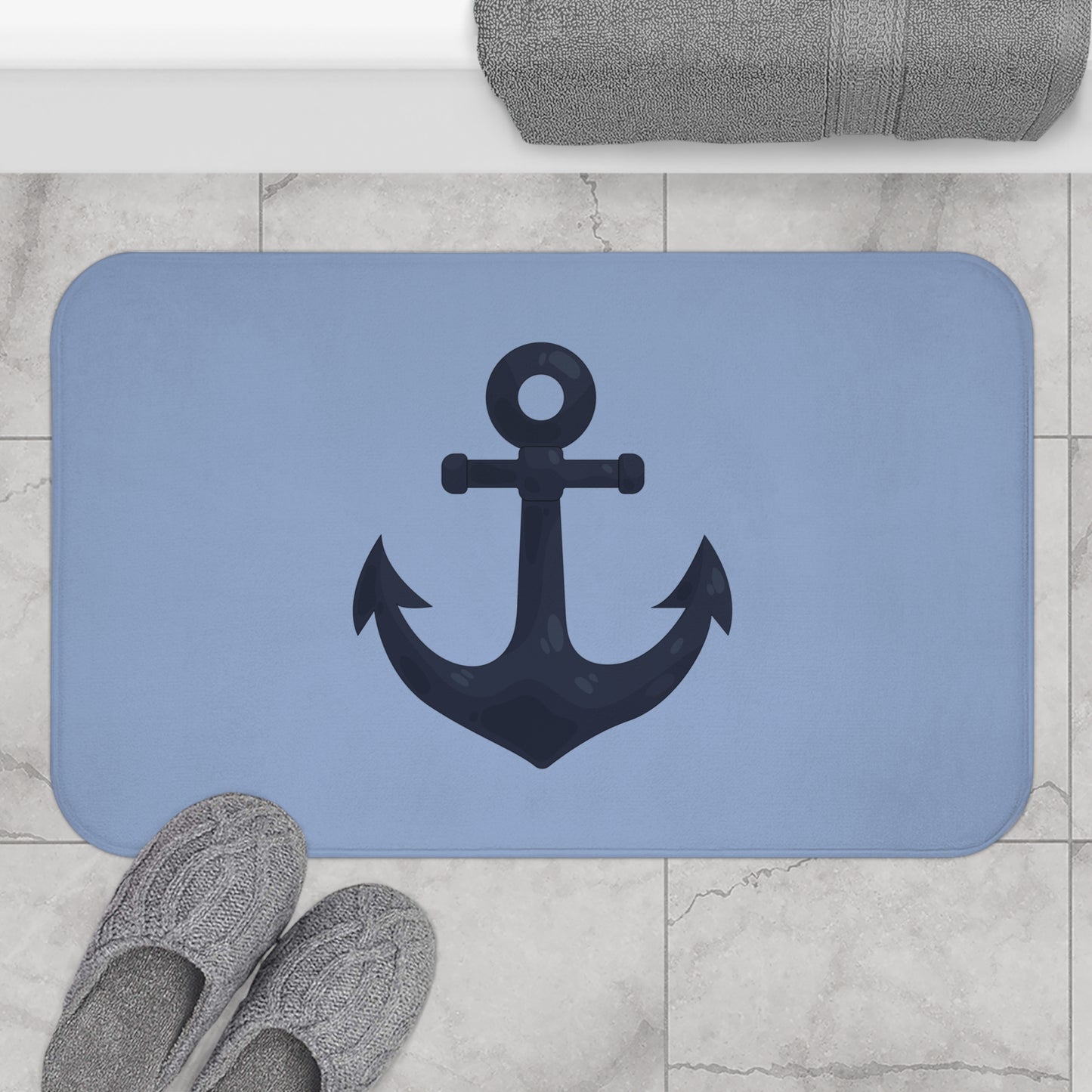 Blue bath mat with an anchor design on a tiled bathroom floor.