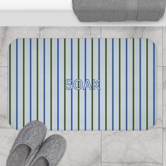 Striped bath mat with 'SOAK' text on a tiled bathroom floor.