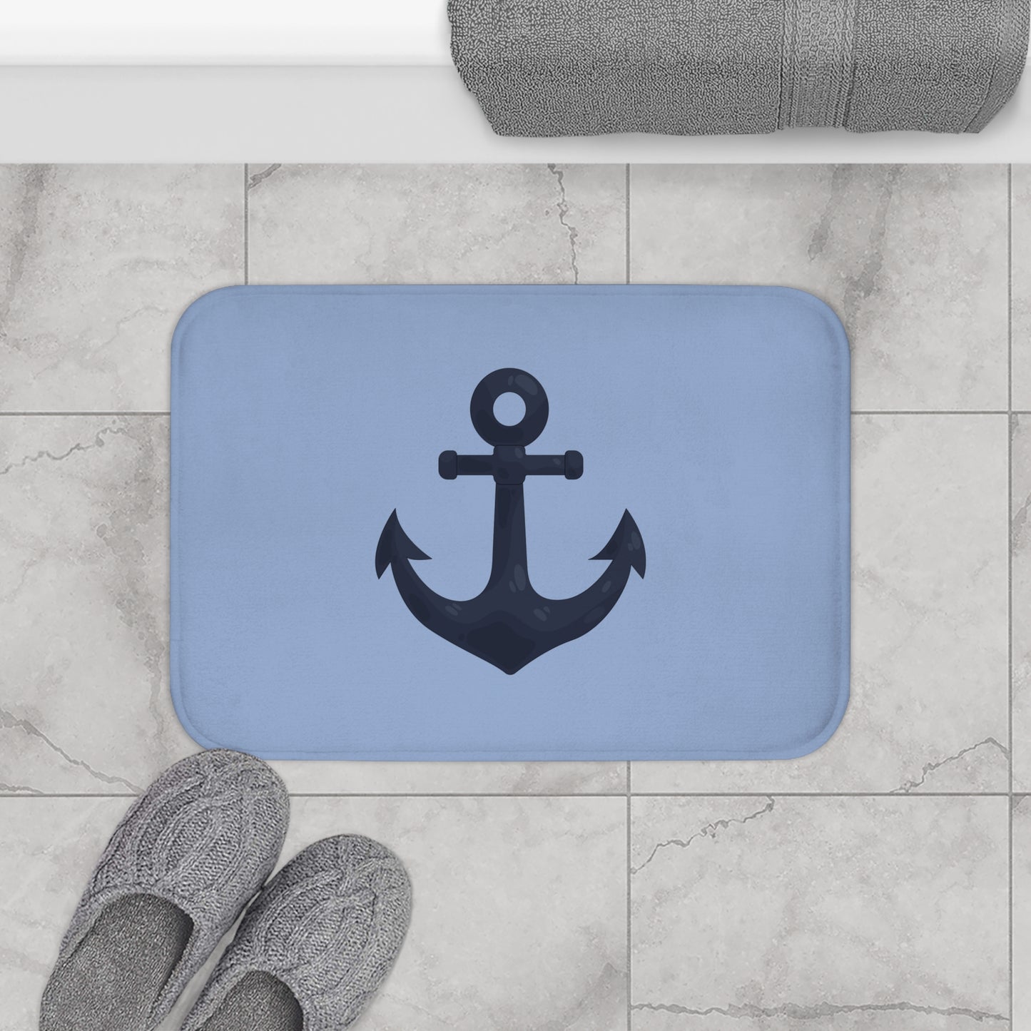Blue bath mat with anchor design on a tiled bathroom floor.