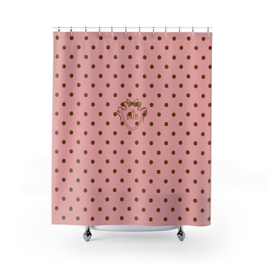 Pink shower curtain with gold polka dots and a logo on a white background