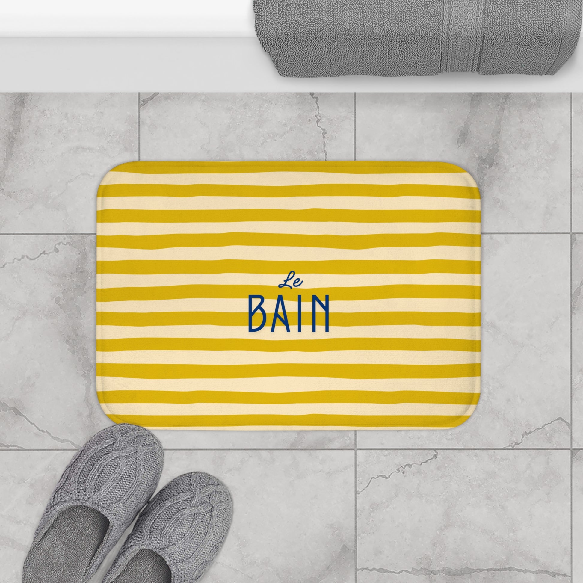 Striped bath mat with 'Le Bain' text on a bathroom floor.
