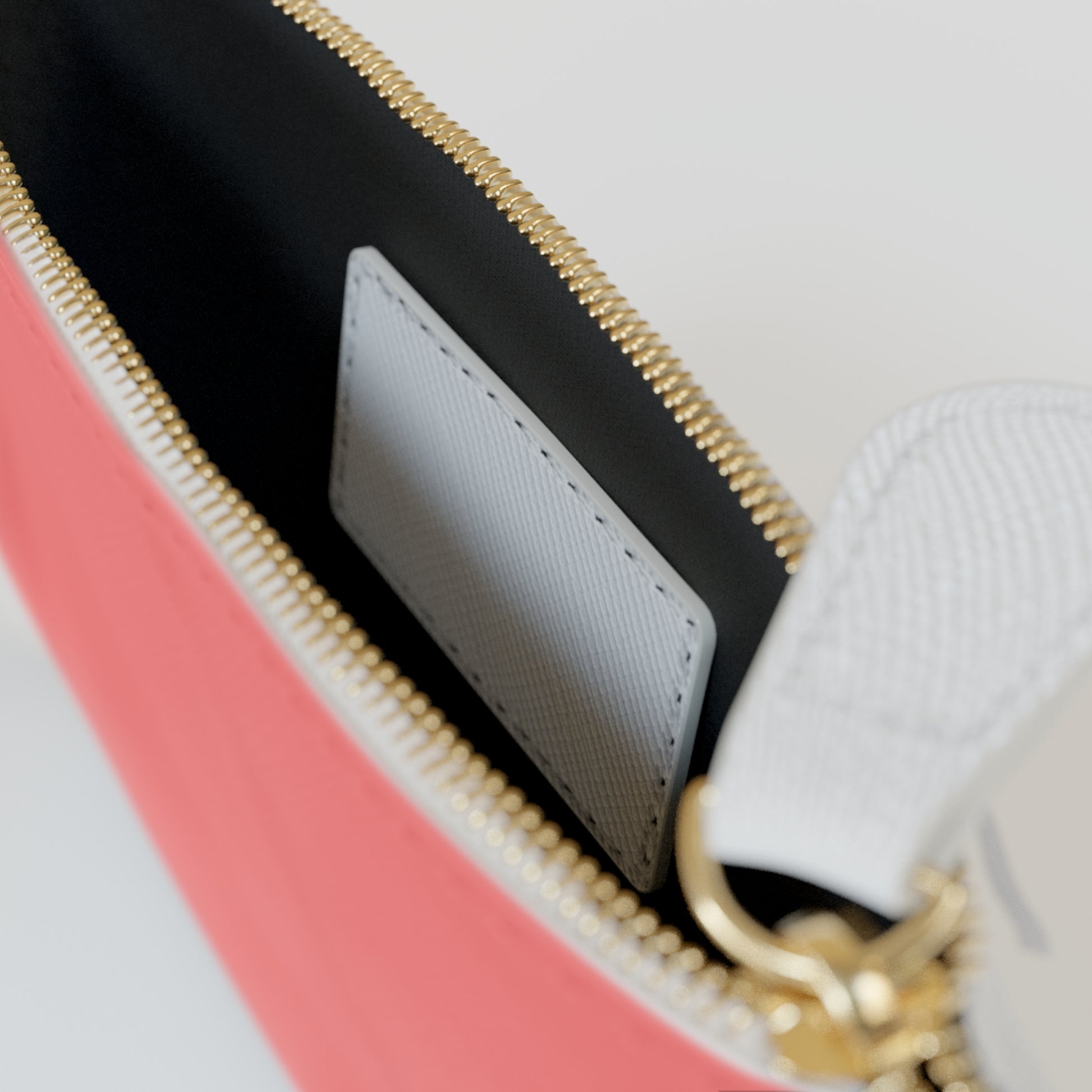 Close-up of a pink and black handbag with gold zipper and handle.