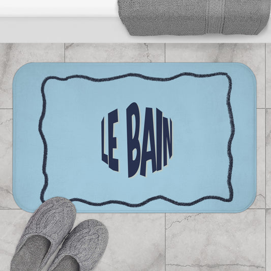 Blue bath mat with 'LE BAIN' text on a bathroom floor.