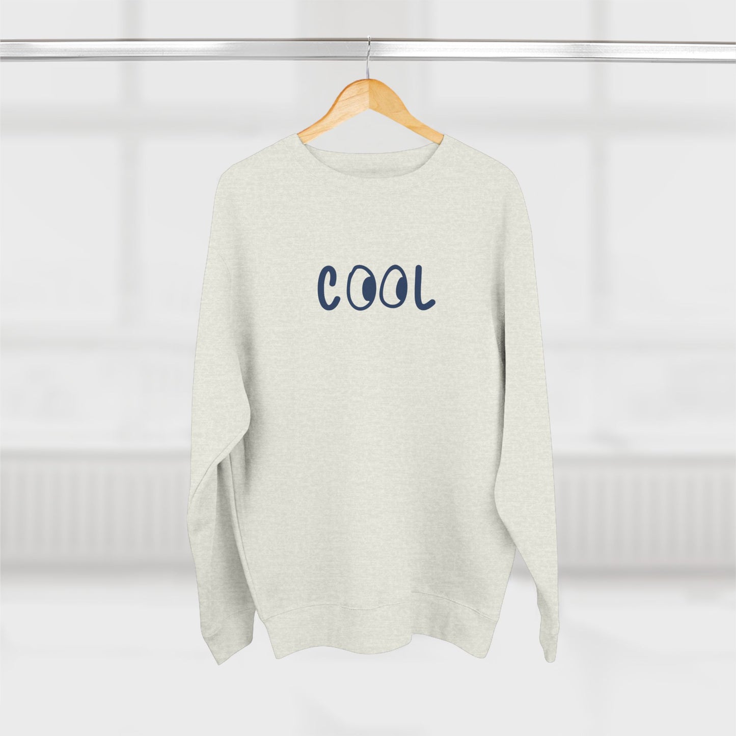 White sweater with 'COOL' text on a hanger against a white background