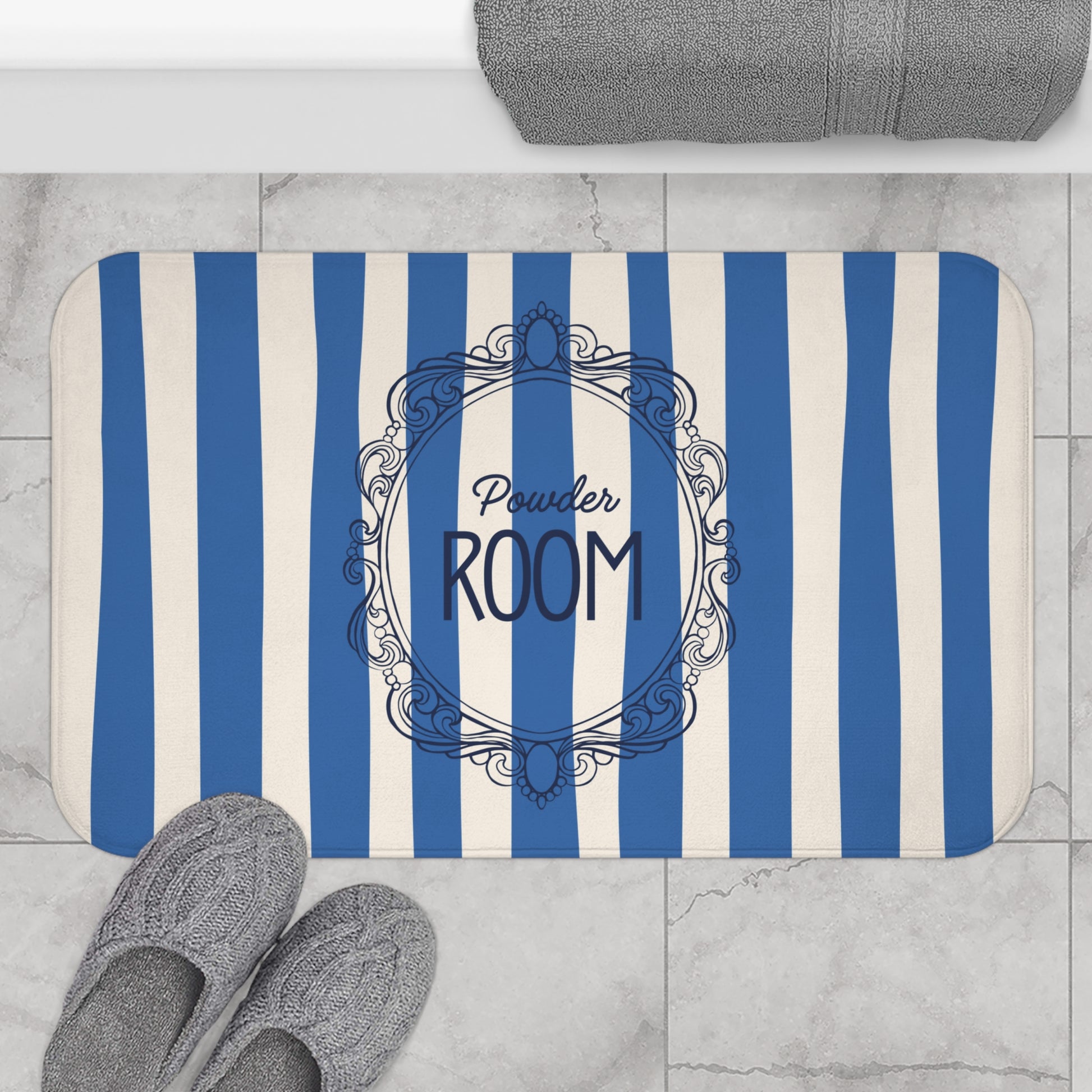 Striped bath mat with 'Powder Room' text on a bathroom floor.
