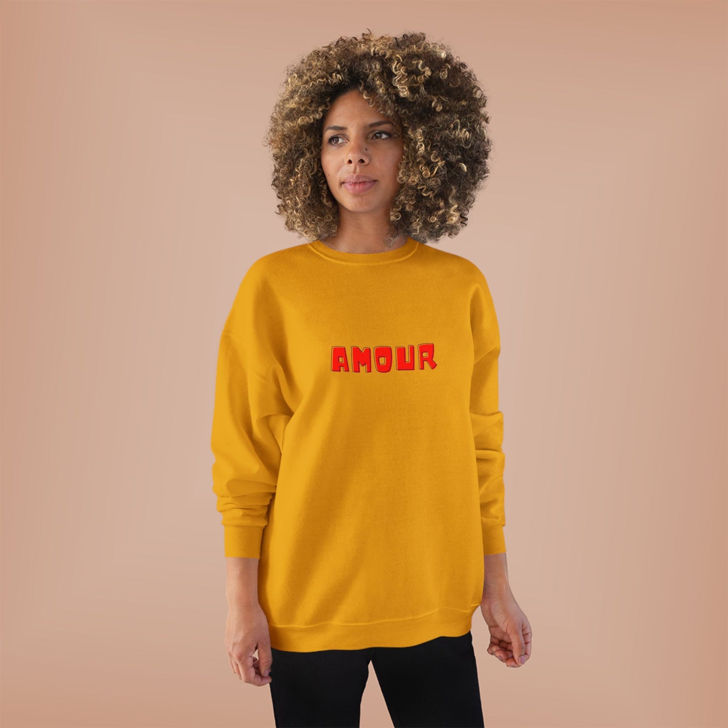 Woman wearing a yellow sweatshirt with 'AMOUR' printed in red on a beige background