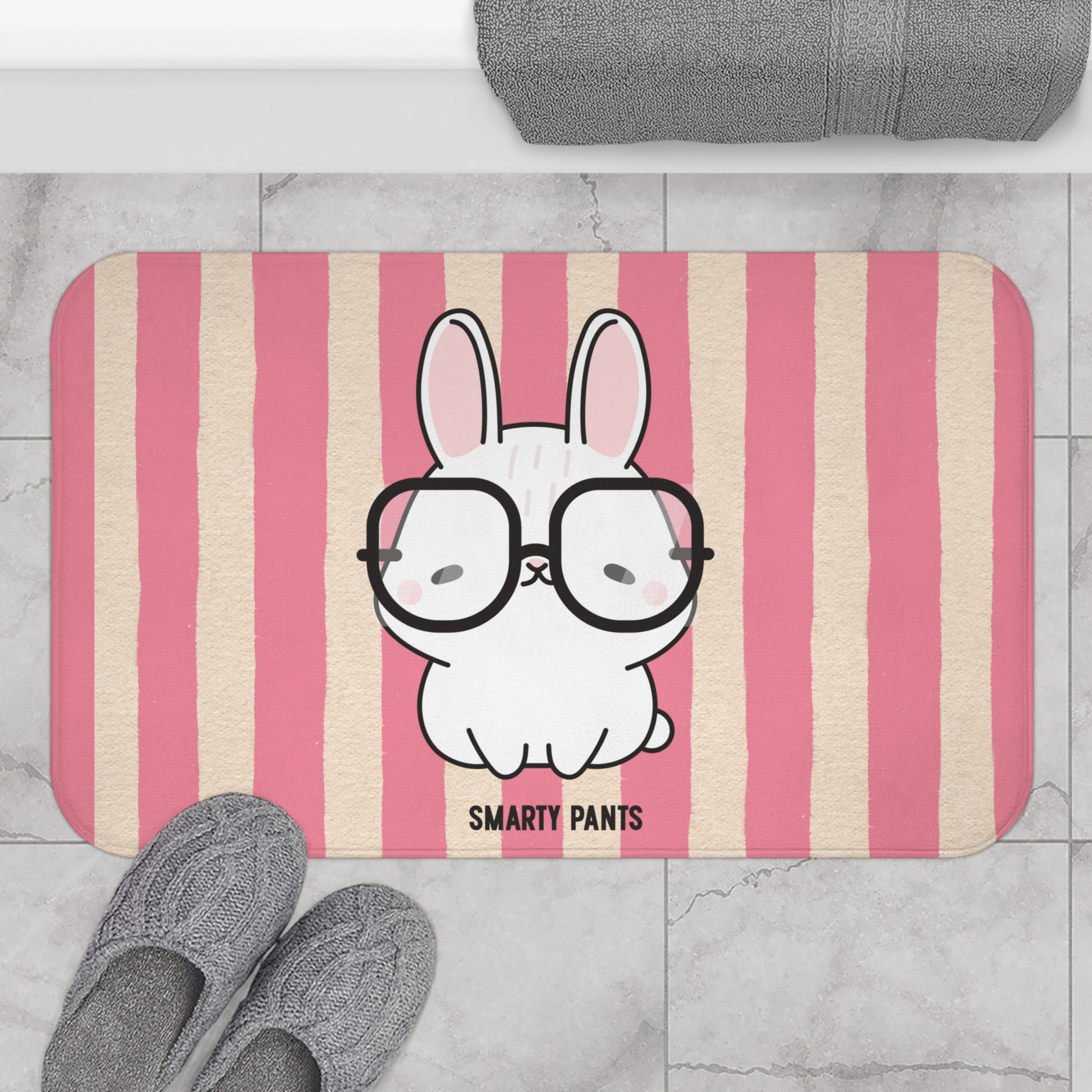 Striped bath mat with a cartoon bunny wearing glasses and the text 'Smarty Pants' on a bathroom floor.
