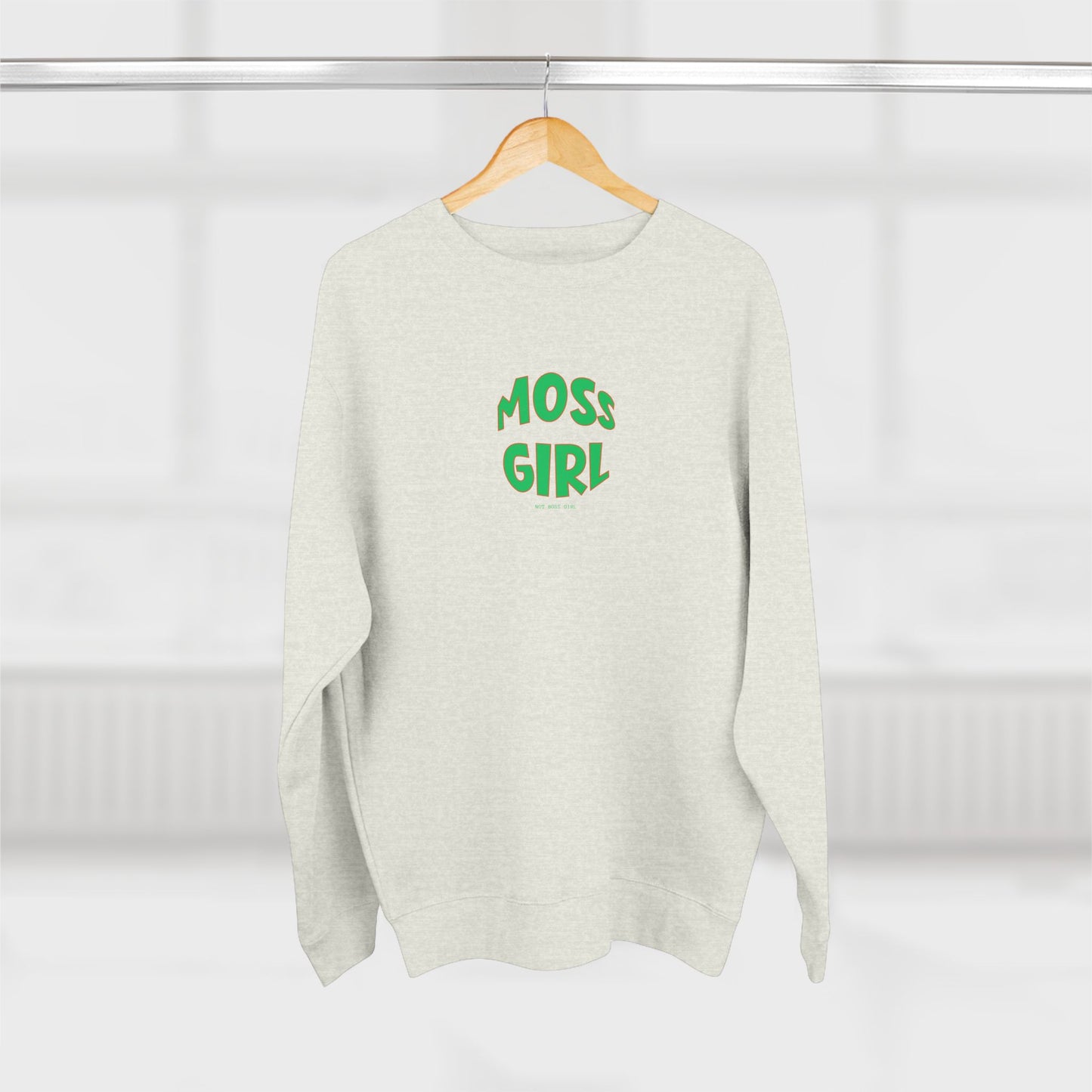 White sweater with 'MOSS GIRL' text in green on a hanger against a white background
