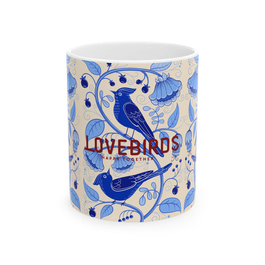 A white ceramic mug featuring a blue floral and bird pattern on a cream background, with the words 'LOVEBIRDS HAPPY TOGETHER' printed in red and blue across the front.