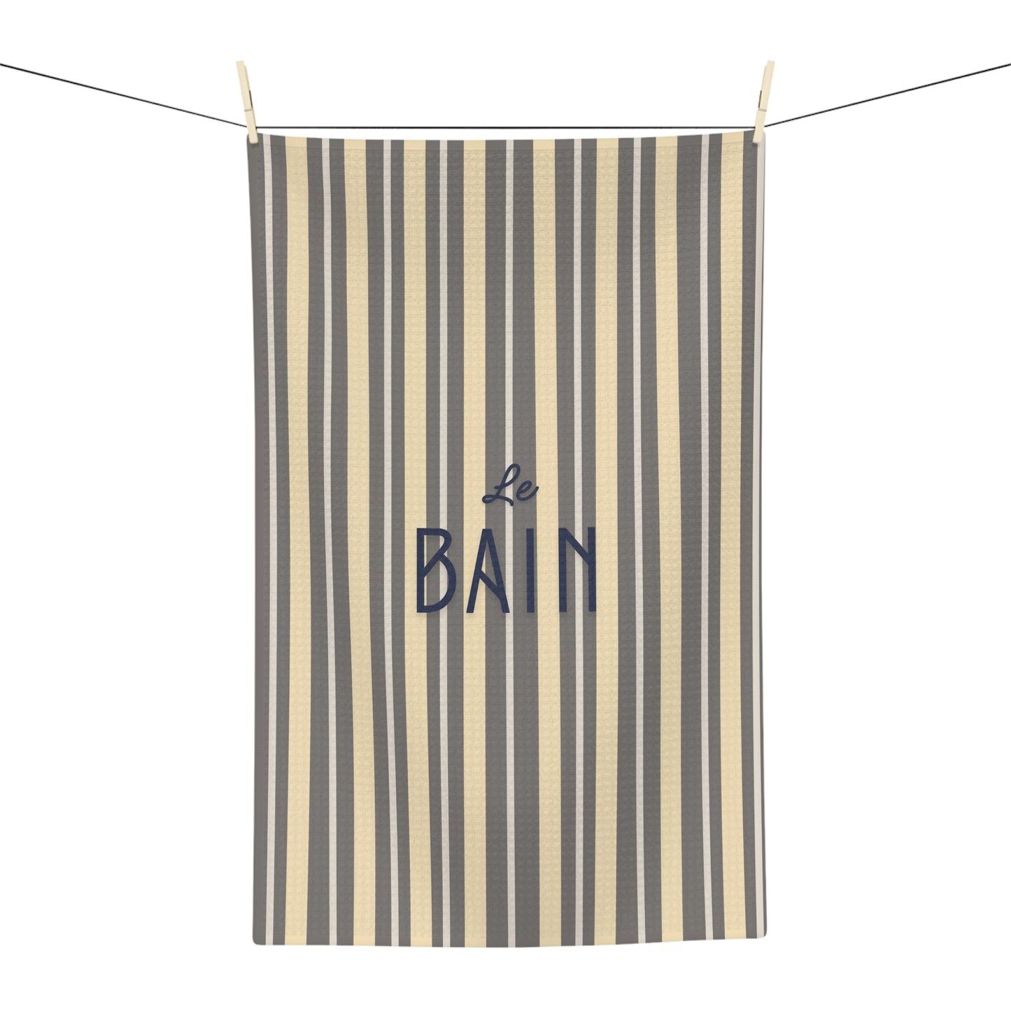 Striped towel with 'Le Bain' text hanging on a line