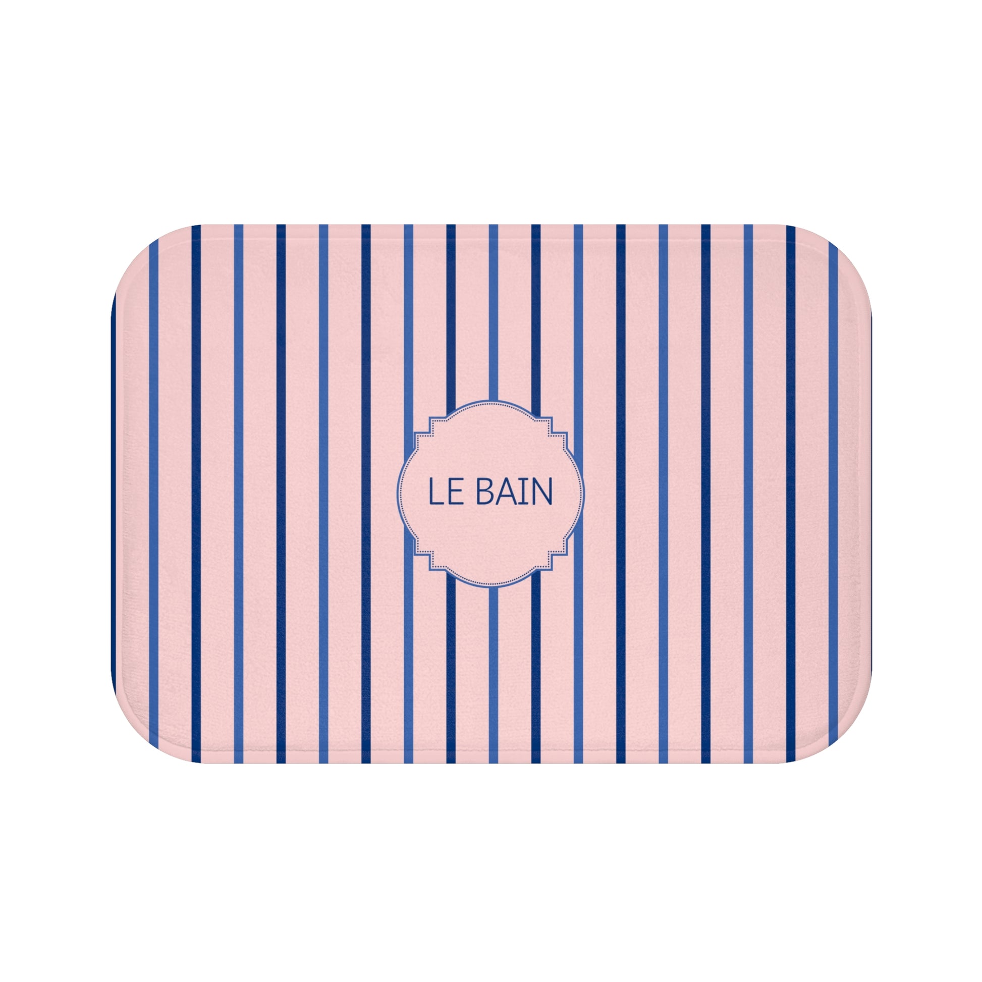 A rectangular bath mat with rounded corners, featuring vertical navy blue and light pink stripes with a central pink label that reads 'LE BAIN' in navy text.