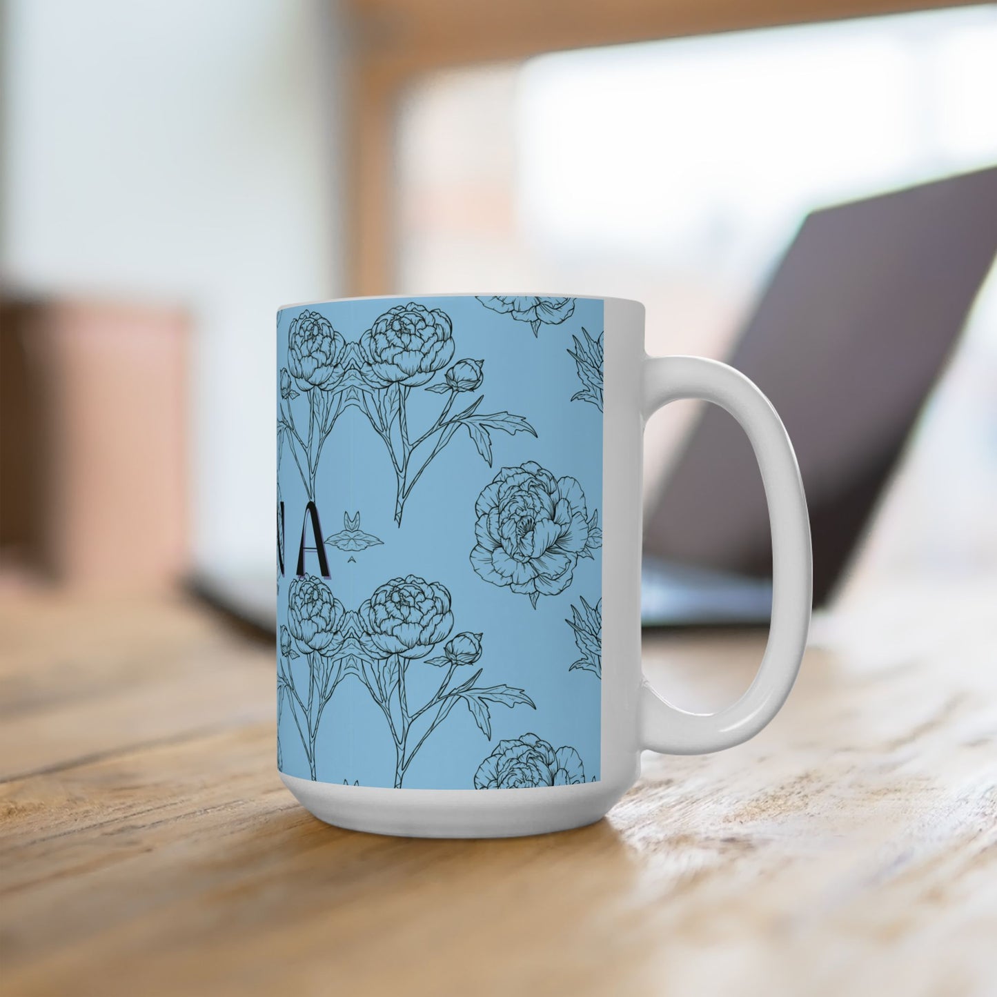 White mug with floral pattern on a light blue background, placed on a wooden surface.