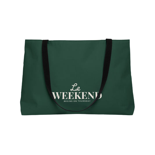 Green tote bag with 'Le Weekend Begins on Thursday' text on a white background