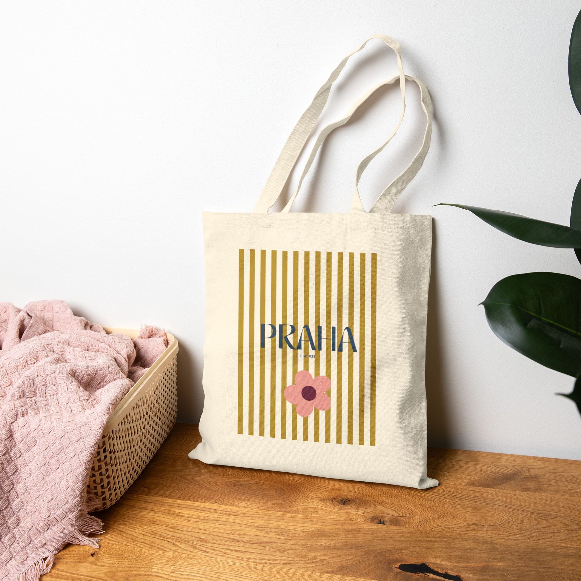 Tote bag with 'PRAHA' and a flower design on a wooden surface with a plant in the background