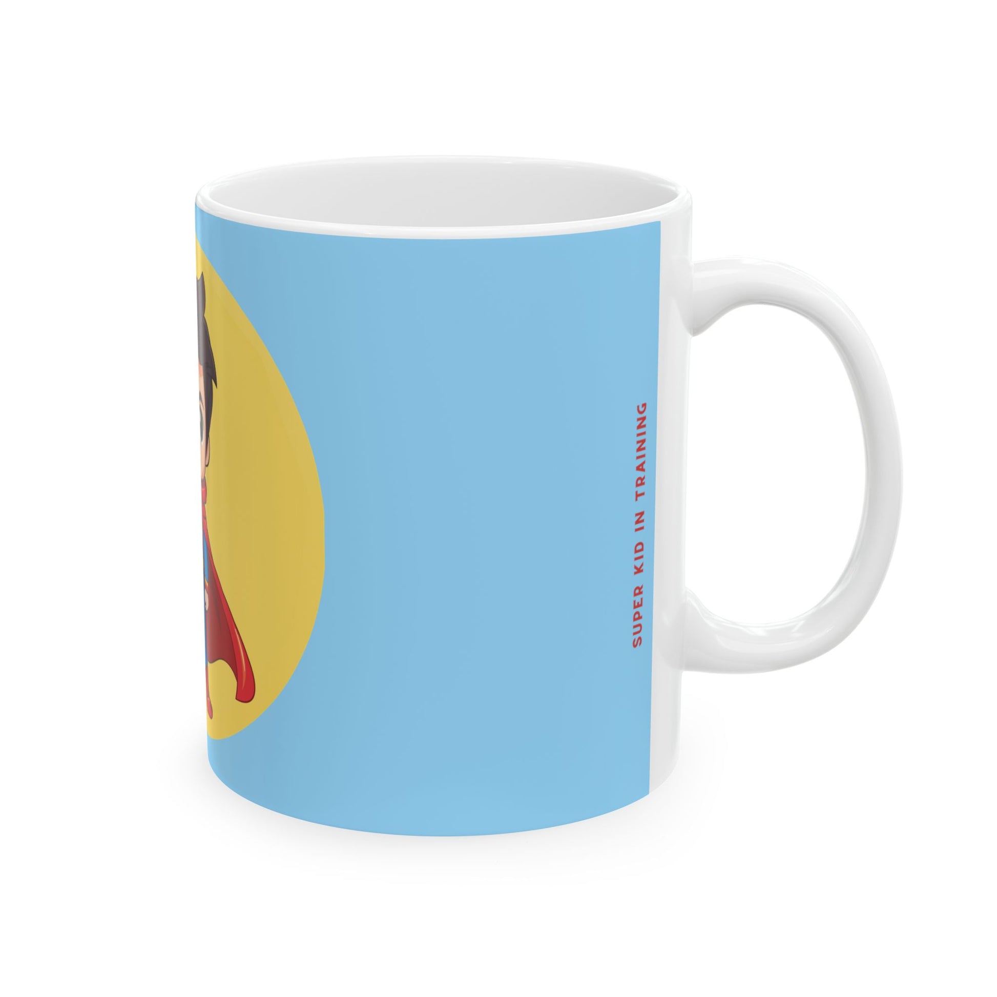 A white ceramic mug with a light blue printed wraparound design, featuring a partial graphic of a person in a red and yellow outfit, and vertical red text reading 'SUPER KID IN TRAINING'.