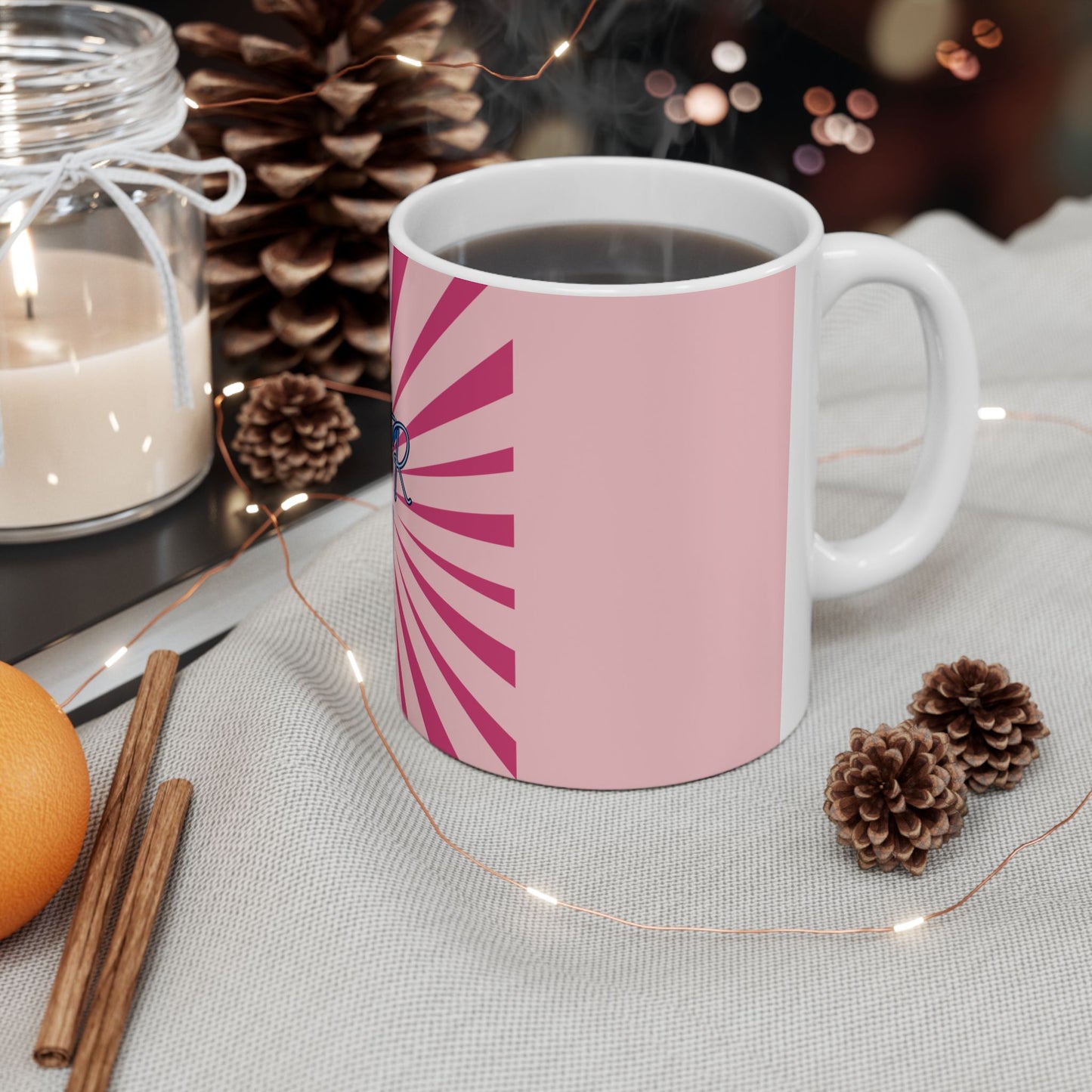 White mug with pink design on a table with decorative items